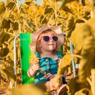 Un copil într-un câmp de floarea-soarelui într-o zi de vară